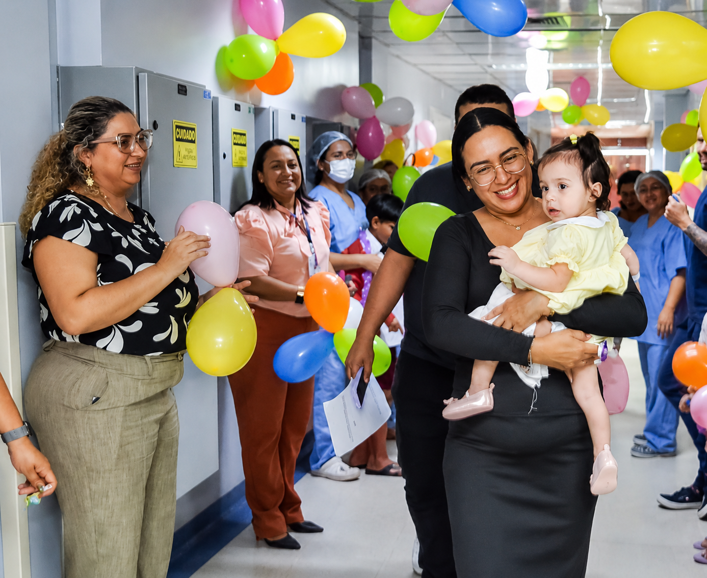 Comemoração com balões no corredor do Hcor, com colaboradora carregando uma bebê no colo